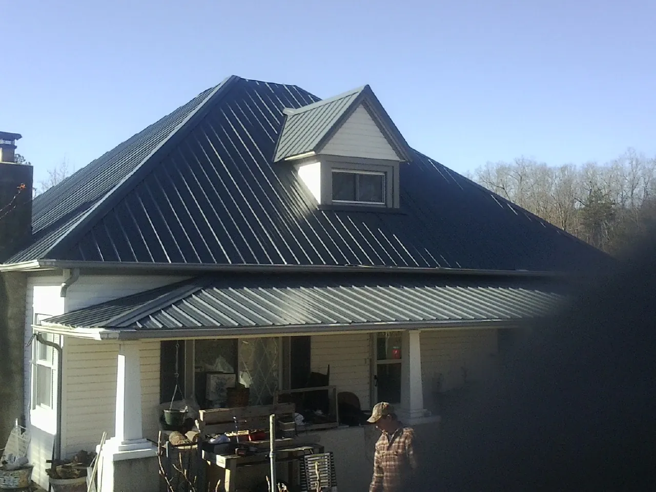 Dark blue standing seam metal roof with a dormer above a front porch in Casey