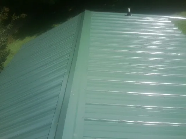 New green metal panels meeting at the ridge of a roof — Flat Roof Repair work by our crew in Casey
