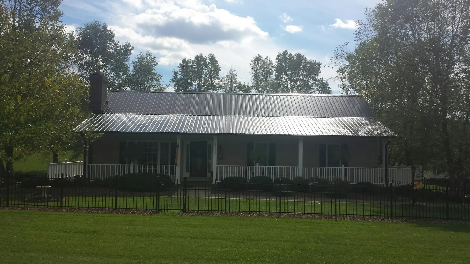 Gray metal roof on a brick ranch with a full width front porch — Gutter Guard Installation work by our crew in Casey