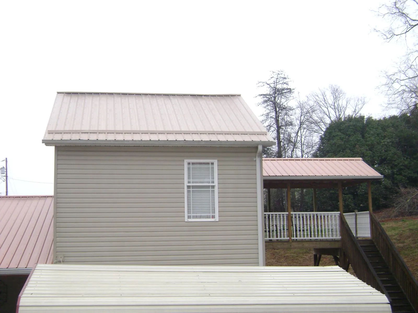 Tan metal roofs on a two story addition and attached porch, from a Roof Replacement job in Casey