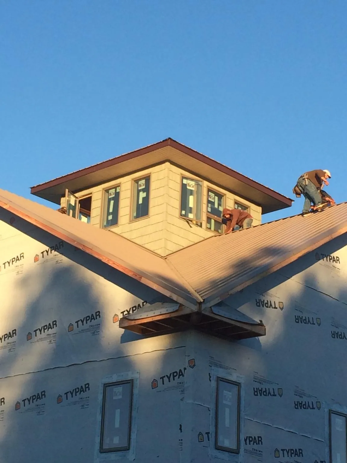 Roofers working around a rooftop cupola on a new metal roof at sunset — Roof Waterproofing in Casey by Roofing Brothers